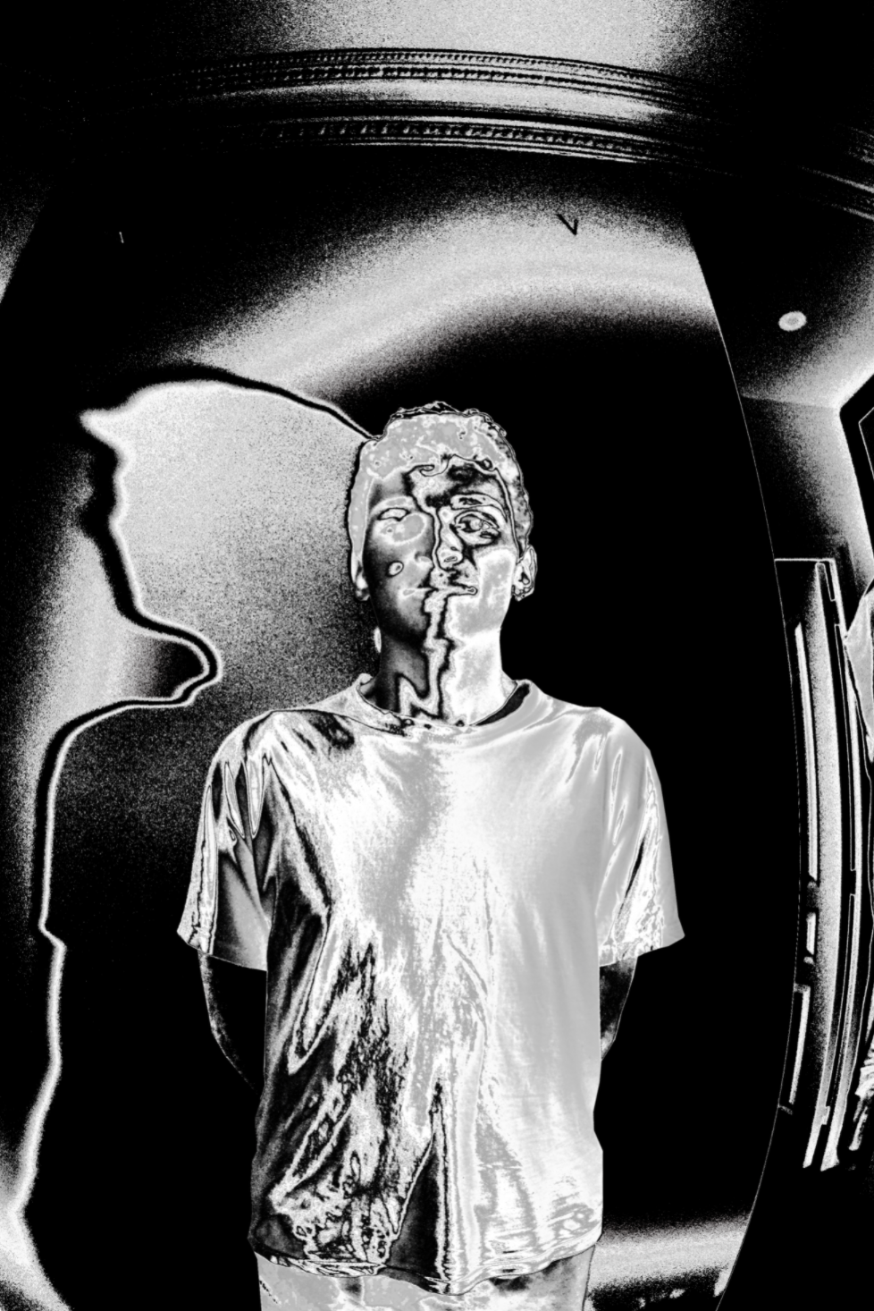 In the photo there is an artistically edited representation of a person in black and white, whose photo has been heavily edited so that the face is no longer recognizable. The person has short hair and wears a T-shirt. The background is noisy and an artificial shadow has been added.